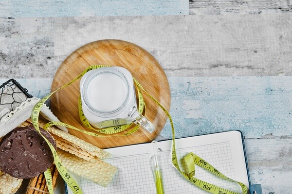 Hur naturliga kosttillskott hjälper till med viktminskning 4 korg kex burk mjolk marmor bord med anteckningsbok